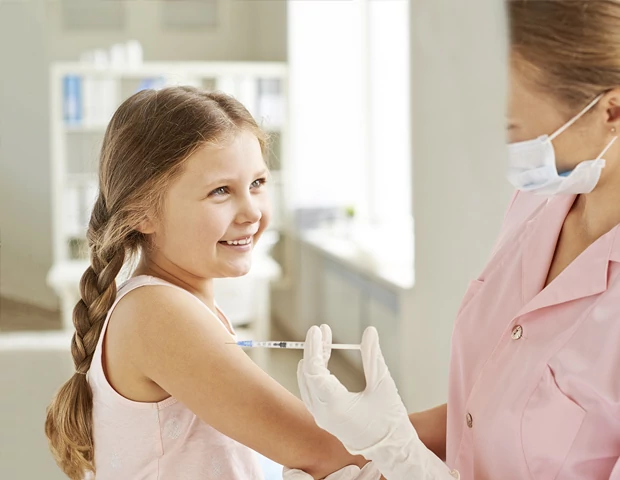 Criança feliz toamando vacina no braço